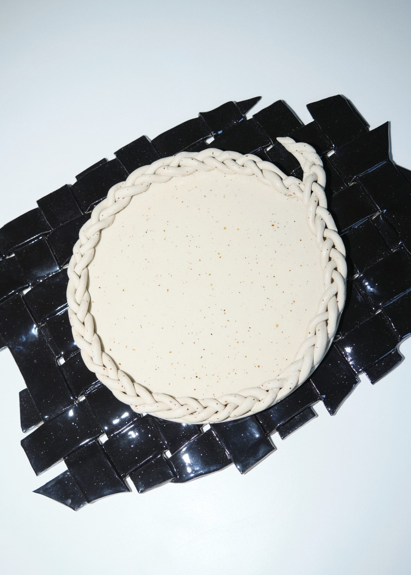 Ceramic plate with braided edge on black leather weave